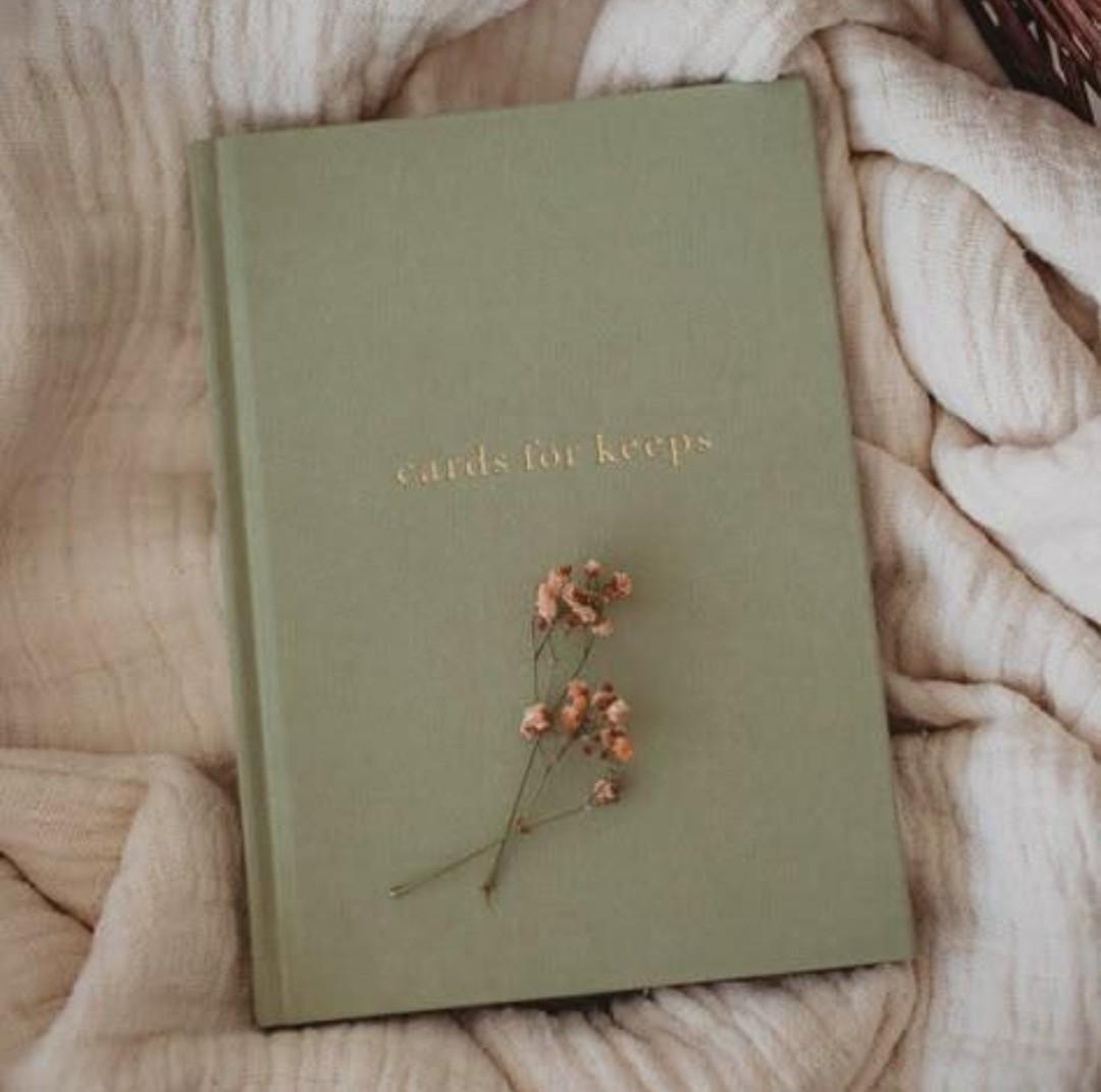 A sage green journal resting on soft fabric with small flowers
